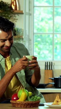 Indian asian young husband and wife having coffee in modern kitchen platform with light hearted chit chat enjoying their morning beverage and talking together in a relaxed home environment