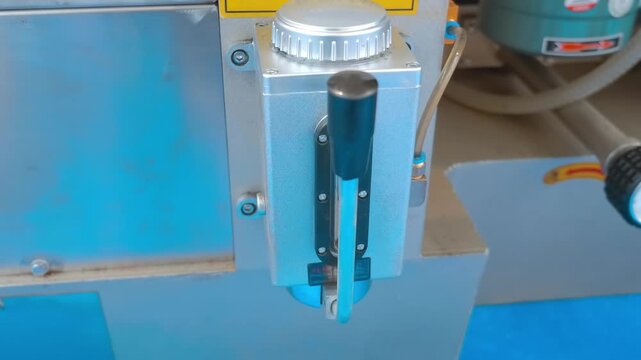 An oiler on industrial equipment; when the lever is pressed, oil flows in a volume that is visible on the meter. Closeup. Shot in motion