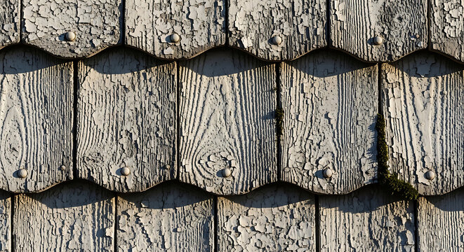 Closeup of weathered asbestos cement siding shingles with peeling paint on a vintage home illustrating hazardous materials requiring professional remediation and