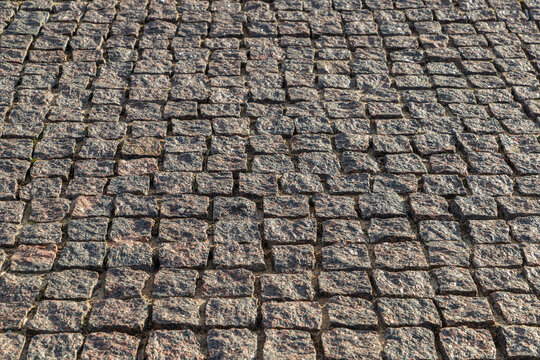 Grunge brown grey granite tiled walking path. Tiled retro pavement or square in old city.