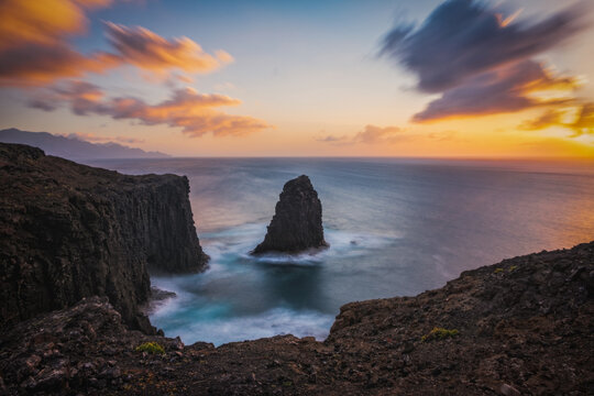 Outcropping rock known as Roque partido or Farallon de Tabata in Gran Canaria island, Canary Islands, Spain. Long exposure picture at sunset. March 2026
