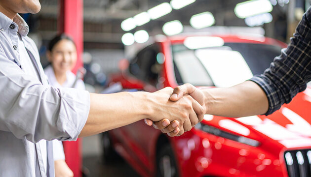 Hands of happy car owner discussing vehicle repair with mechanic beside bright red car trust and positive customer experience in well lit contemporary automotive workshop 