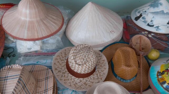 Vietnamese bamboo non la conical hats with colorful drawings and other hats are sold as souvenirs at the street vendors shop