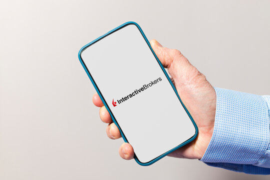 Hand holding smartphone displaying interactive brokers app logo