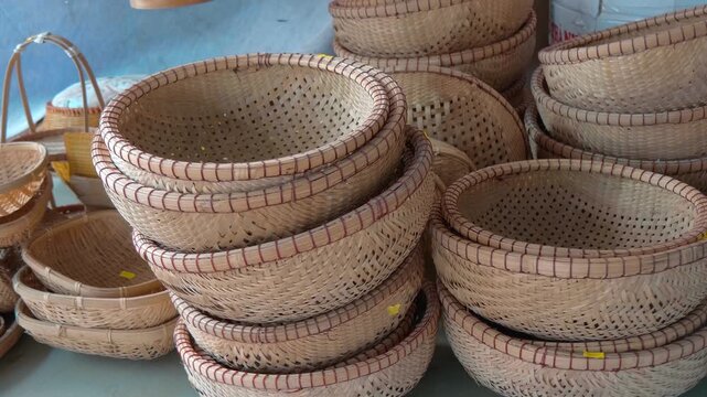Traditional handcrafted flat bamboo baskets, commonly used in Asia for various household tasks such as storing grains or winnowing piled in stacks
