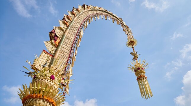 Balinese Penjor, a traditional ornate bamboo pole decoration for religious festivals, against a clear blue sky.