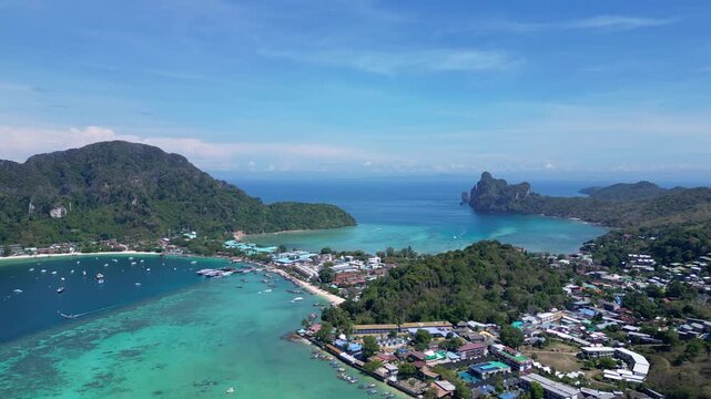 Phi Phi Island, Thailand : Aerial drone footage of Phi Phi Island with busy seafront with resorts surrounded by limestone cliff and turquoise lagoon on a sunny day in southern Thailand in southeast As