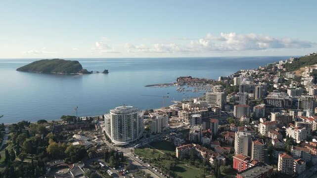 Aerial view flying backward showcasing a scenic town panorama and sea coast of Budva, Montenegro.