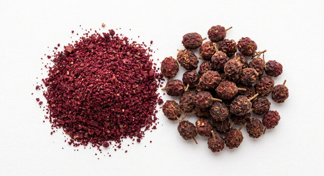 Raw ground sumac and dried berries on white background