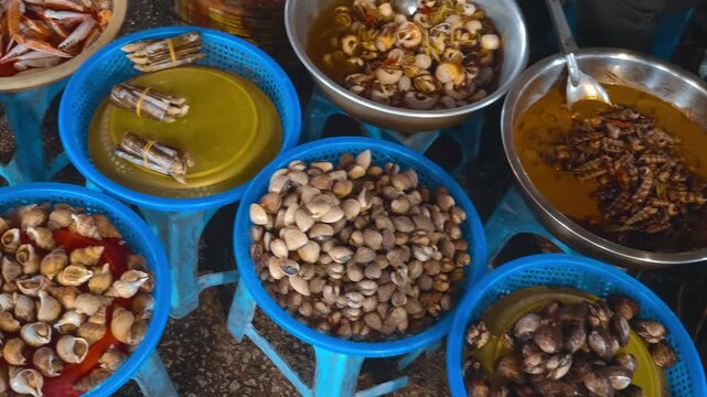 Local delicacies in basins, including fresh clams, razor clams, crab claws, cockles, snails, and various shellfish are sold on the popular tourist spot - Da Lat night market, Vietnam

