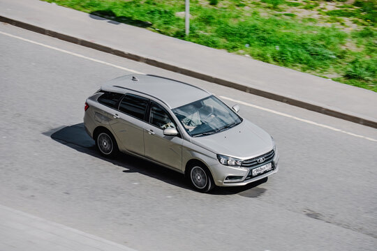 Lada Vesta SW station wagon moving in the street. Beige car in motion, above front side view