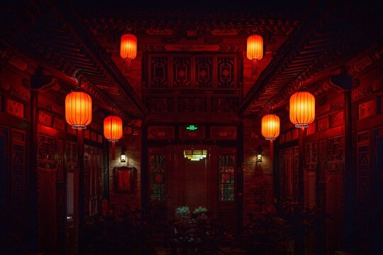 Traditional Chinese courtyard illuminated by glowing red lanterns at night