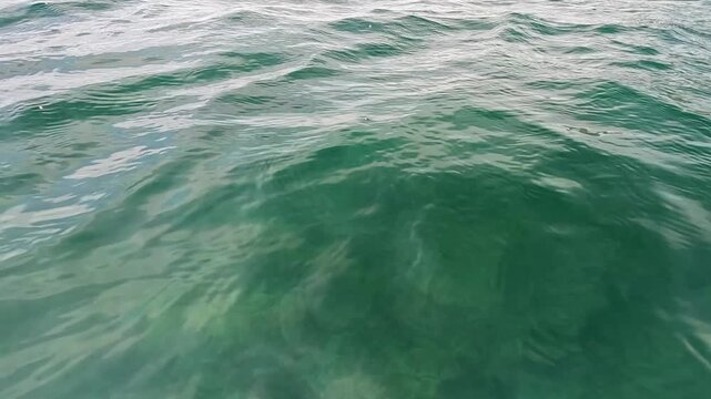 Ocean water ripples emerald green seawater waves flow gently across the surface during a sunny day to create a peaceful atmosphere