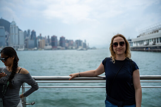Two women enjoying a scenic view of Hong Kong's skyline from a waterfront promenade