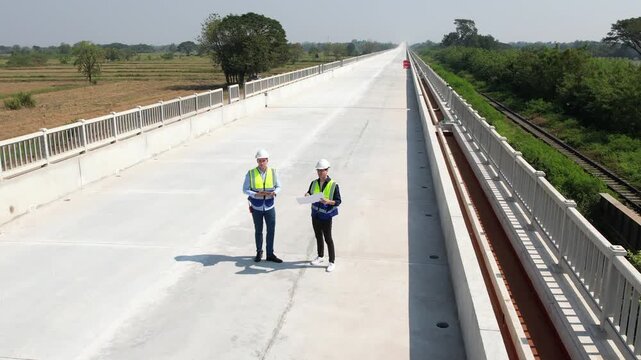 Bridge construction inspection engineer worker safety helmet vest roadway infrastructure wide bridge road construction site with engineering survey planning concrete deck and empty elevated bridge