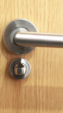 hand opening a door latch bathroom at home