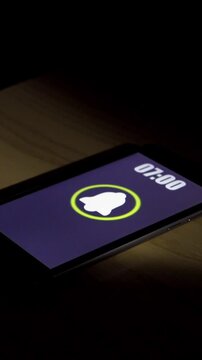 Smartphone alarm clock app rings for wake up, screen shows at bedroom