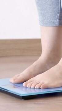 Woman weighing herself on a scale at home and throwing measuring tape on the blue scale.