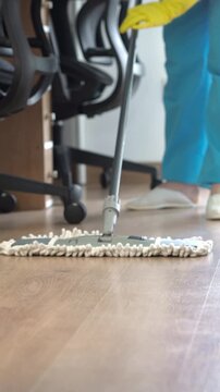 Close-up of an unrecognizable woman mopping the office floor