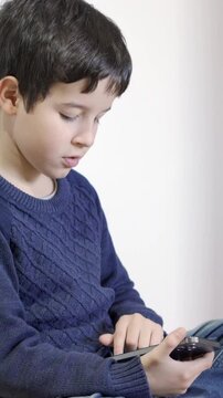 A little boy playing with a smartphone at home.