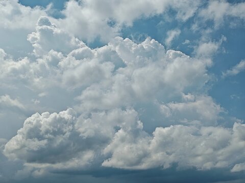 A beautiful landscape of fluffy white clouds filling a clear blue sky during a bright sunny day.