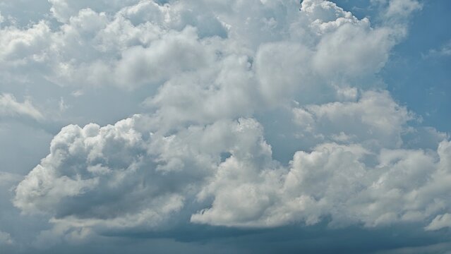 A beautiful landscape of fluffy white clouds filling a clear blue sky during a bright sunny day.