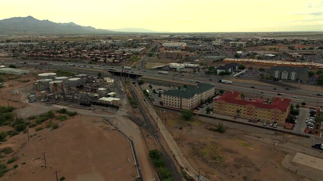 Desert city flyover with refinery infrastructure highway and mountain backdrop