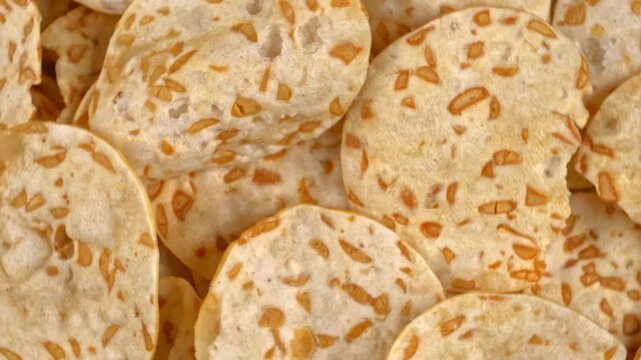 Rotating macro background showcasing crispy tempeh chips texture and irregular shapes