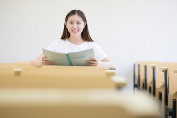 Naklejka premium Smiling Female Student Reading in Classroom