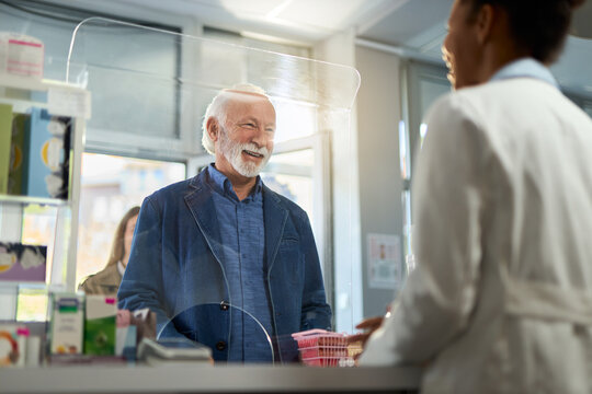 Smiling mature man talking to a pharmacist while buying a medicine in a drugstore