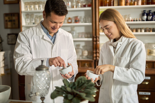 Young smiling students of science making homeopathic medicine in a laboratory