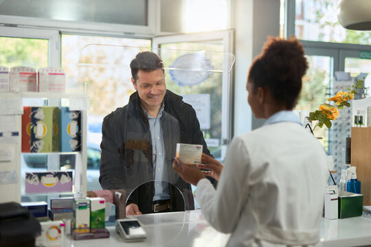 Smiling mid adult man talking to a pharmacist while buying a medicine in a drug store