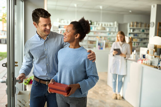 Happy diverse couple going out of drugstore after buying medicines