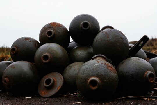 Old unexploded bombs piled up together. Rusty military shells show signs of age. Ammunition waits for disposal or historic display. Danger from past conflicts.