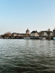 Naklejka premium Seine River in Paris with historic architecture and Institut de France skyline, peaceful urban waterfront view with classic travel atmosphere