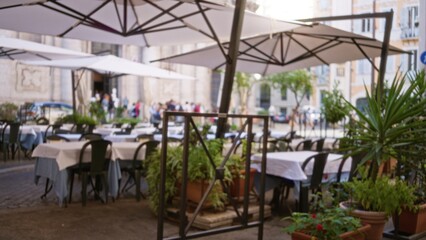 Fototapeta premium Cafe terrace in soft bokeh with defocused tables, umbrellas and potted plants; background backdrop copyspace calm.