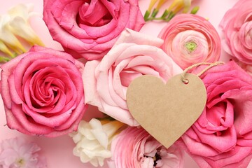 Fototapeta premium Beautiful flowers and blank heart shaped card on pink background, top view. Space for text