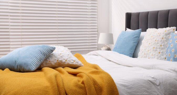 Soft cushions in colorful pillowcases on bed indoors