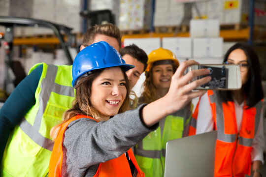 Warehouse workers taking a selfie together, wearing safety gear