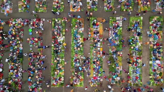Top down aerial drone view of crowded traditional market in Vietnam. Colorful market stalls, local vendors, fresh produce, and busy daily commerce in vibrant urban marketplace scene.
