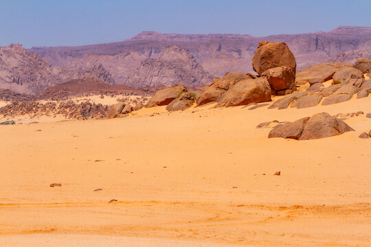 Sahara landscape. Amazing, round rock formations at golden hour. The Tadrart Rouge mountains in the background. Djennet, Algeria, Africa