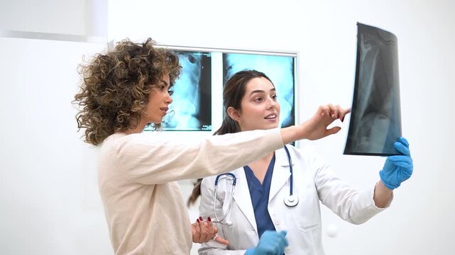Successful Medical Diagnosis. Smiling female doctor discussing positive X-ray results with a happy patient in a clinic. Healthcare and medicine concept. Professional healthcare worker and woman.