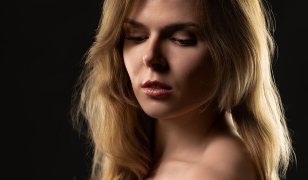 Young woman showcasing glowing skin on a dark background