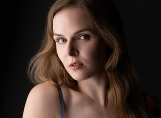 Fototapeta premium Young woman posing in a studio with soft lighting and a dark background