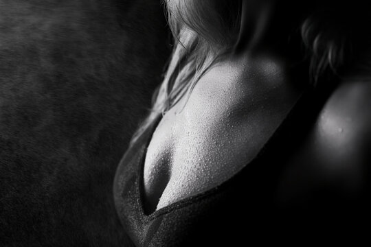 Woman's shoulder and chest with water droplets on skin after intense workout in black and white