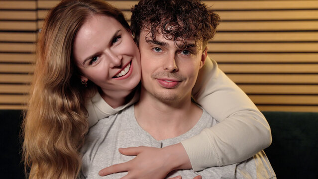 Young adult couple embracing, smiling, and bonding at home