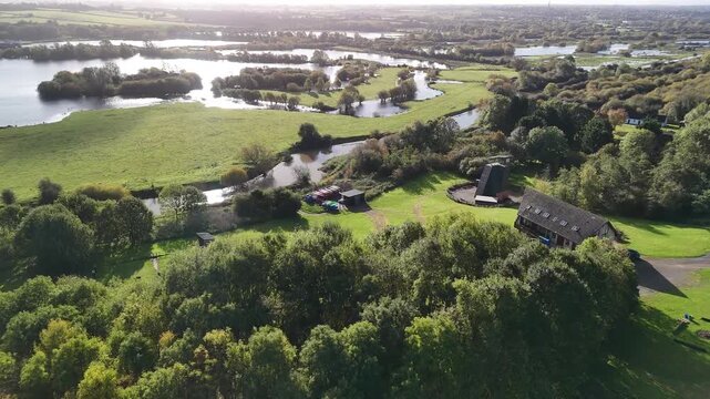 Aerial Sunlit View of River Nene Wetlands with Sun Flare and Lodges in England