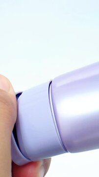 Opening purple serum bottle cap on white background. Close up hands twisting and removing cap. Skincare routine, cosmetic packaging, detailed motion.