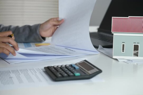 A beautiful property agent opens and checks real estate insurance documents to ensure the validity of the agreement or contract.

