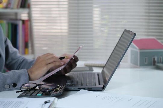 Open and check the printout of savings book, view bank account book in front of laptop, account statement, check payment and income, financial documents, pay slip, cash balance, investment, business.
